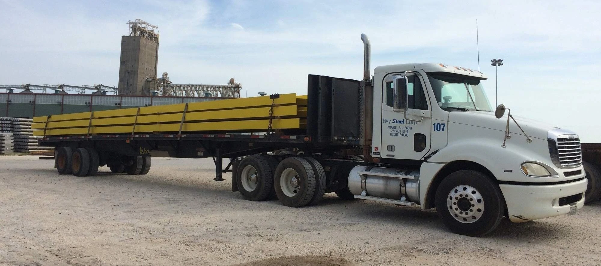 A flatbed truck with yellow cargo parked in an industrial area A flatbed truck with yellow cargo parked in an industrial area